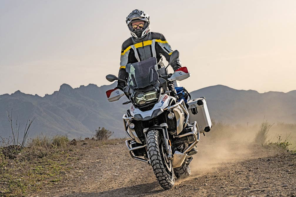 motard sur un trail portant un casque moto adventure